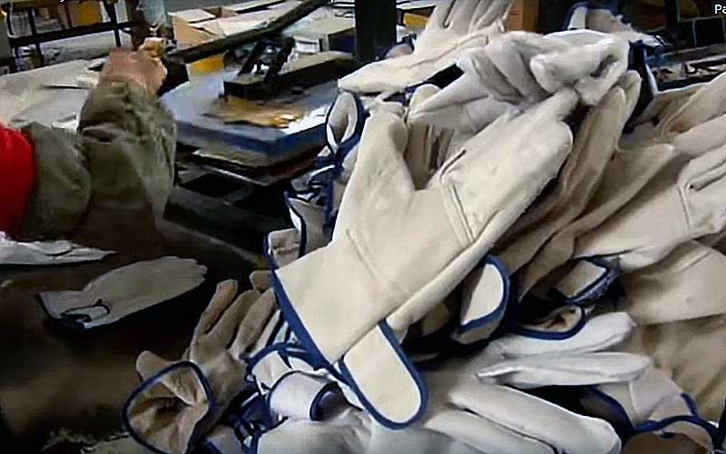 Une pile de gants de travail en cuir blanc disposés dans une usine ou un atelier.